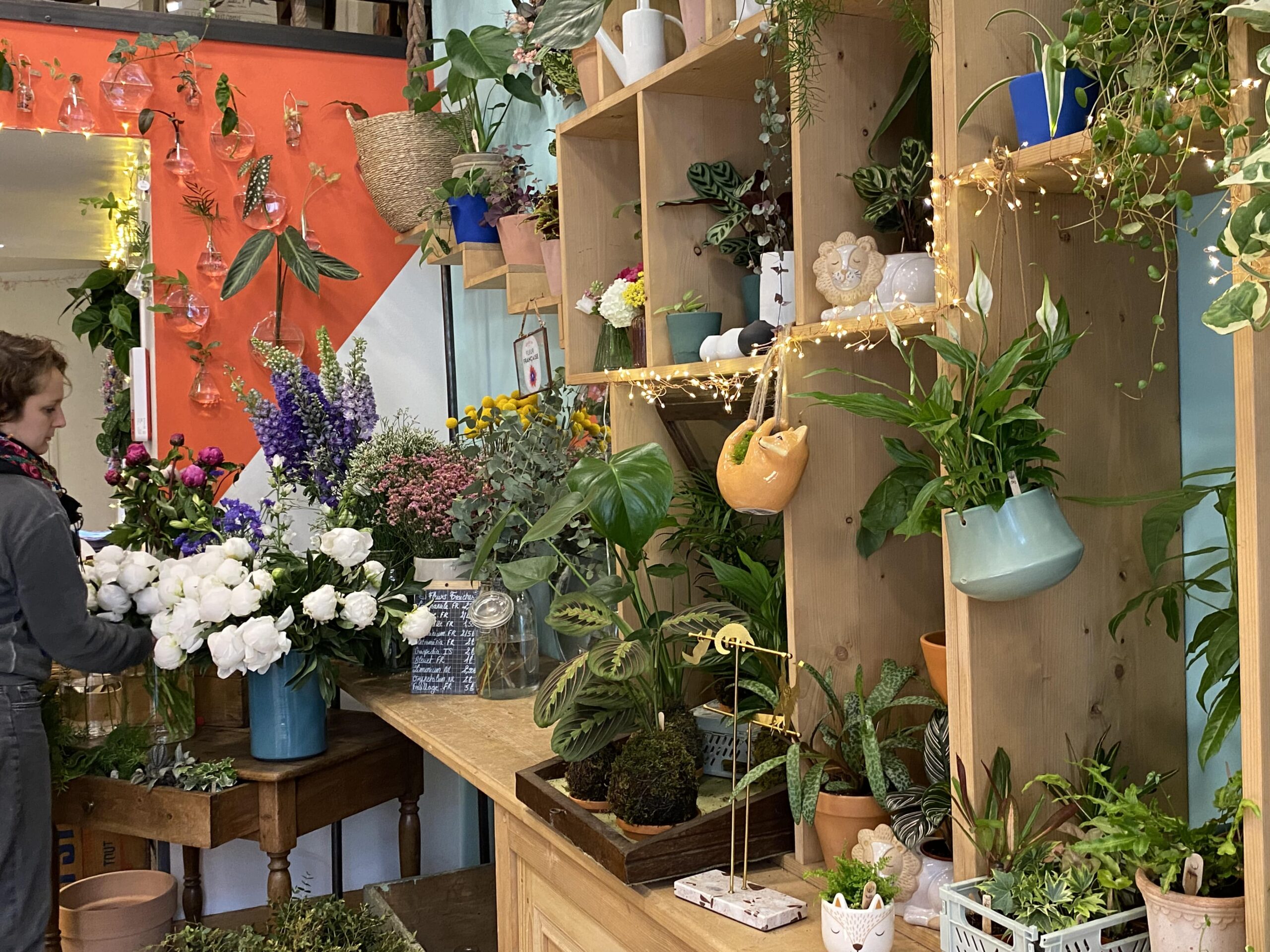 Marion apprête l'étagère de son café-fleurs à Lyon avec un bouquet qu'elle vient d'assembler.